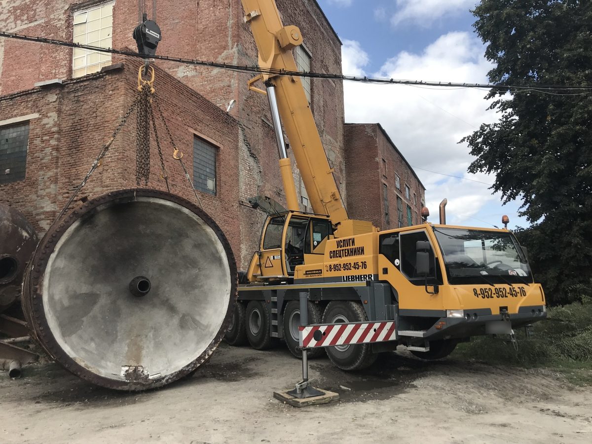 Автокран Liebherr «Высота Сити» поднимает стальную ёмкость у кирпичного цеха